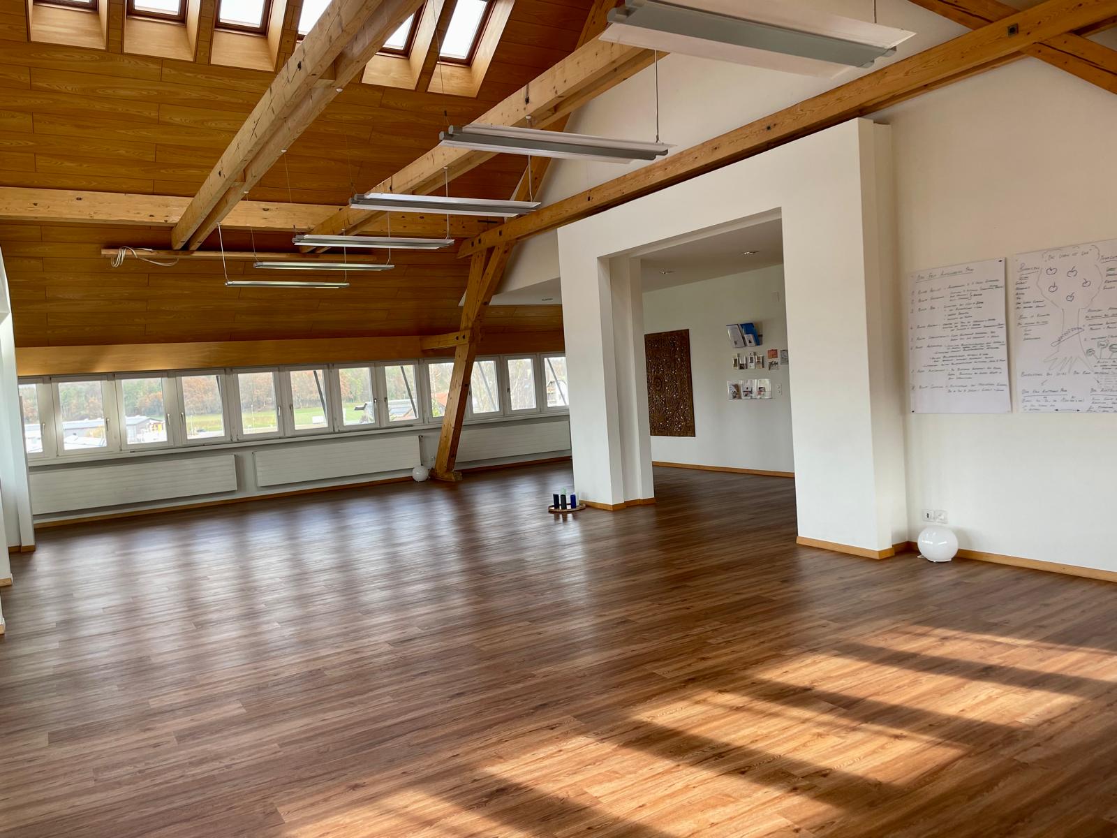 Innenansicht des Kursraums in Eglisau: heller Raum mit Holzboden, Matten und Kissen für Workshops